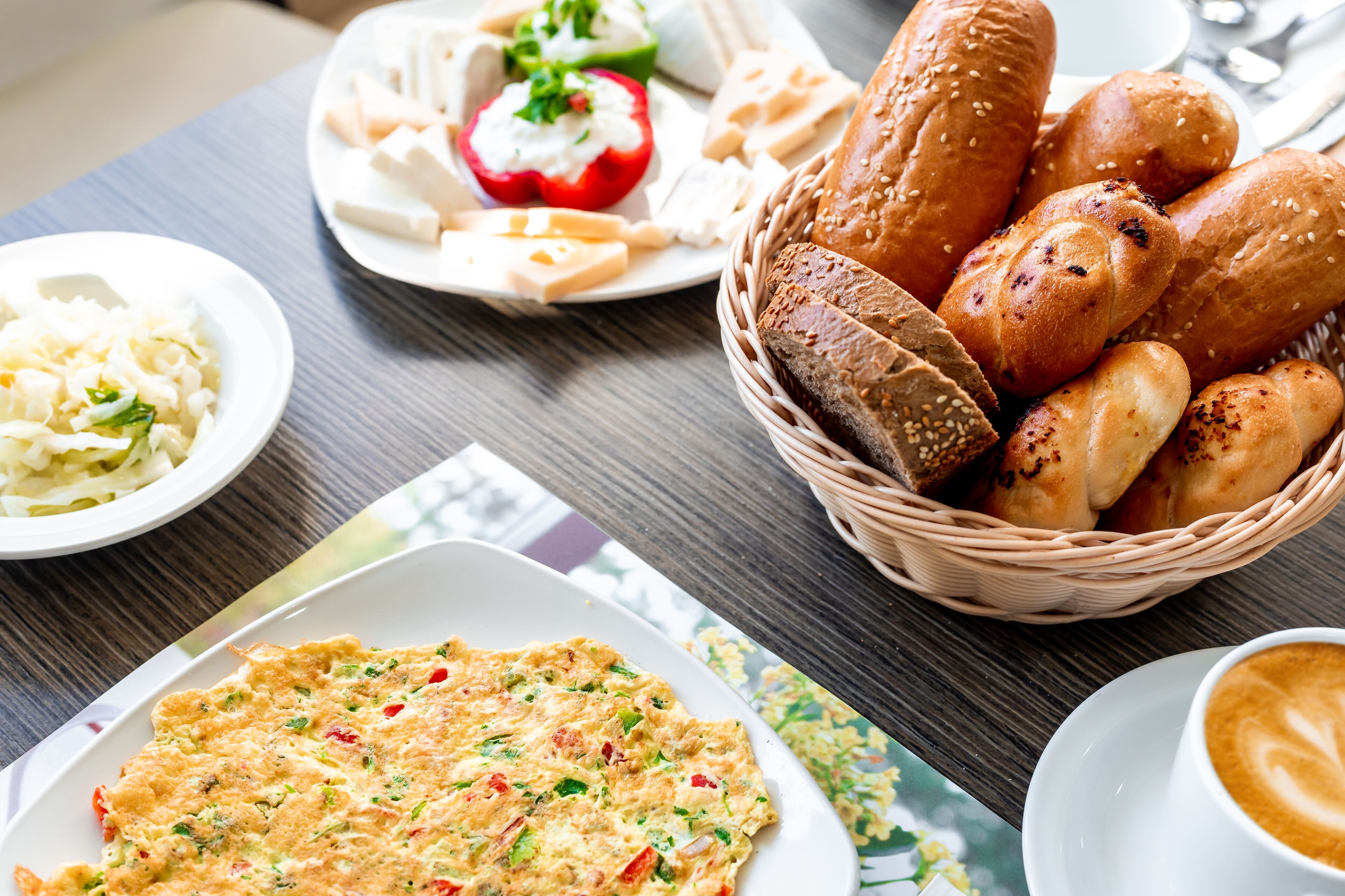 Une table sur laquelle on trouve divers aliments, notamment du pain, une assiette de légumes et une tasse de café.