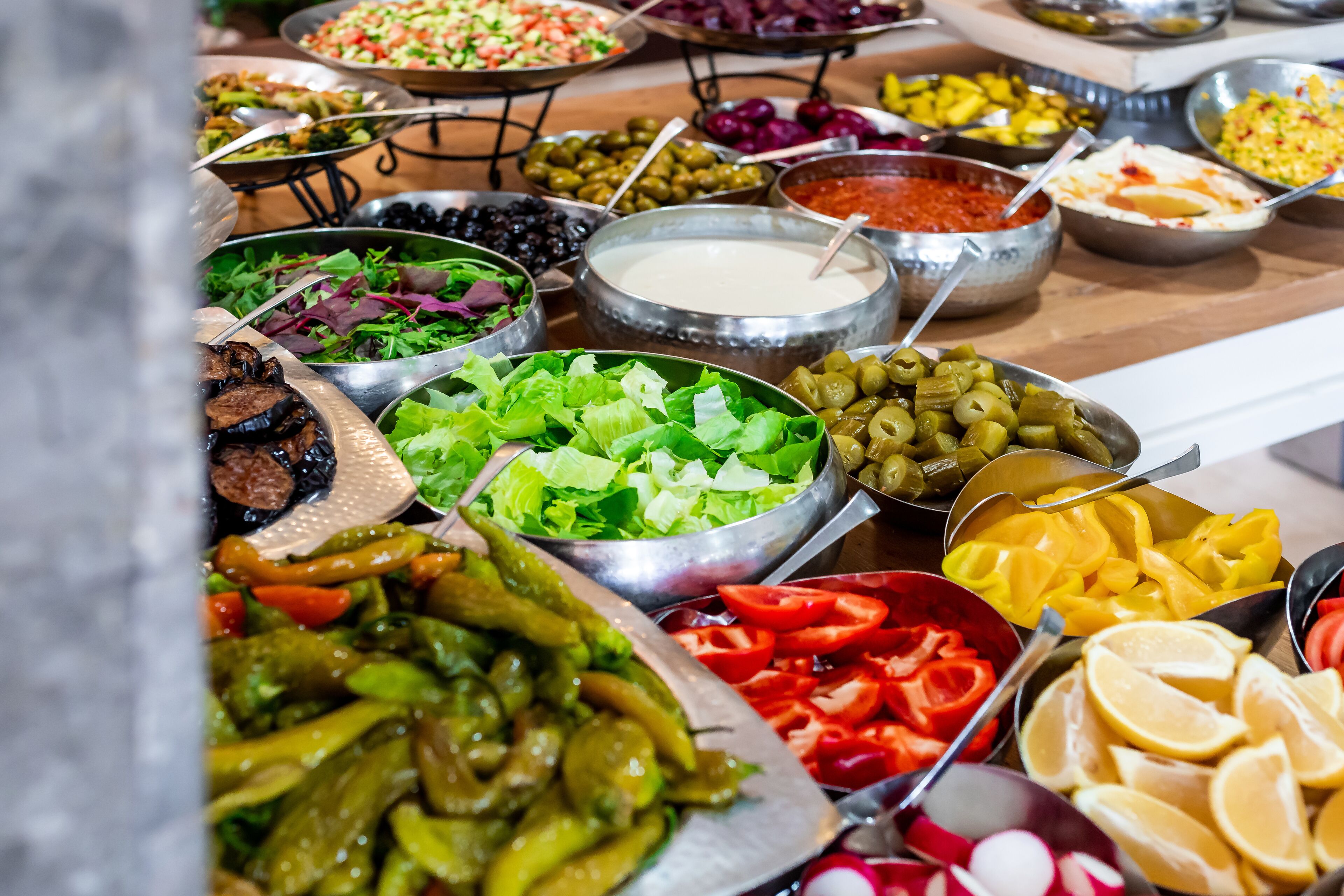 A buffet with various food items including salads, vegetables, and dips.