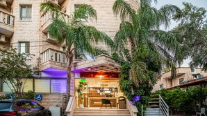 A hotel entrance with a reception desk, a staircase, and a parking area. - Aviv Holiday Flat (Tiberias)