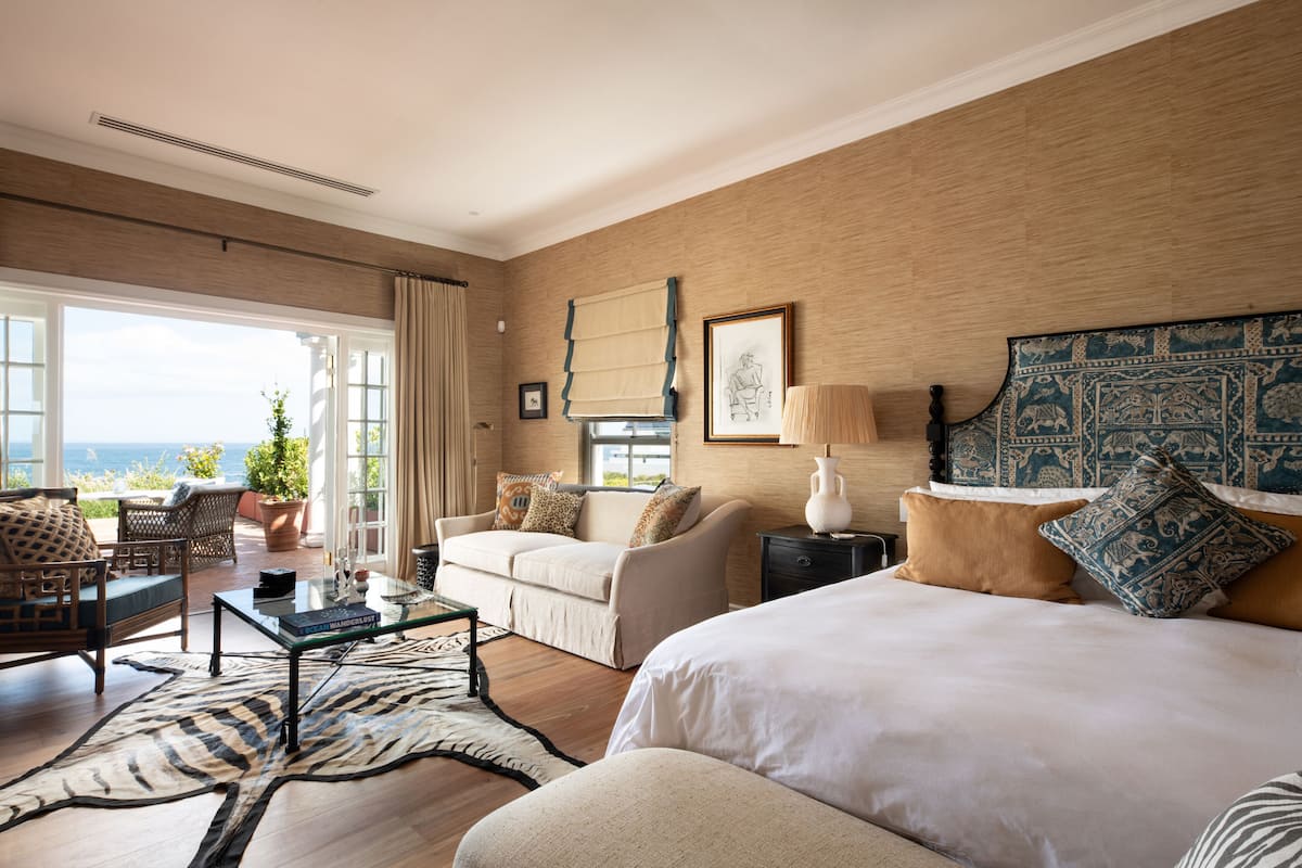Un dormitorio con una cama grande, un sofá, una mesita de centro y vistas al exterior.