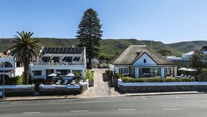 Un hôtel en bord de mer, doté d’un toit de chaume, d’un balcon avec coin salon extérieur et d’une vue sur la mer.