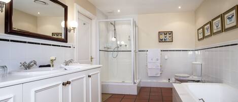 A modern bathroom with a large mirror, two sinks, a shower, and a bathtub.