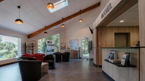 A reception area with a wooden reception desk, a seating area with chairs, and a large window providing a view of the outdoors. - Vvf Villages Argol (Argol)