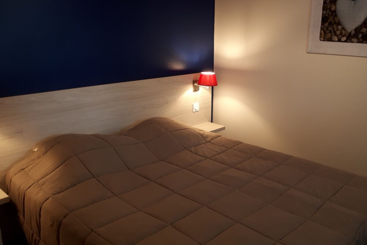 A bed with a headboard, a bedside table with a lamp, and a framed picture on the wall.