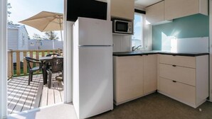 A compact kitchen with a refrigerator, microwave, and a small dining area with a table and chairs. - Vvf Villages Argol (Argol)