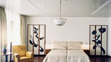 Um quarto com uma cama de casal, uma poltrona amarela, um abajur e um ventilador de teto.