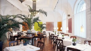 A restaurant with multiple tables, chairs, and a variety of plants.