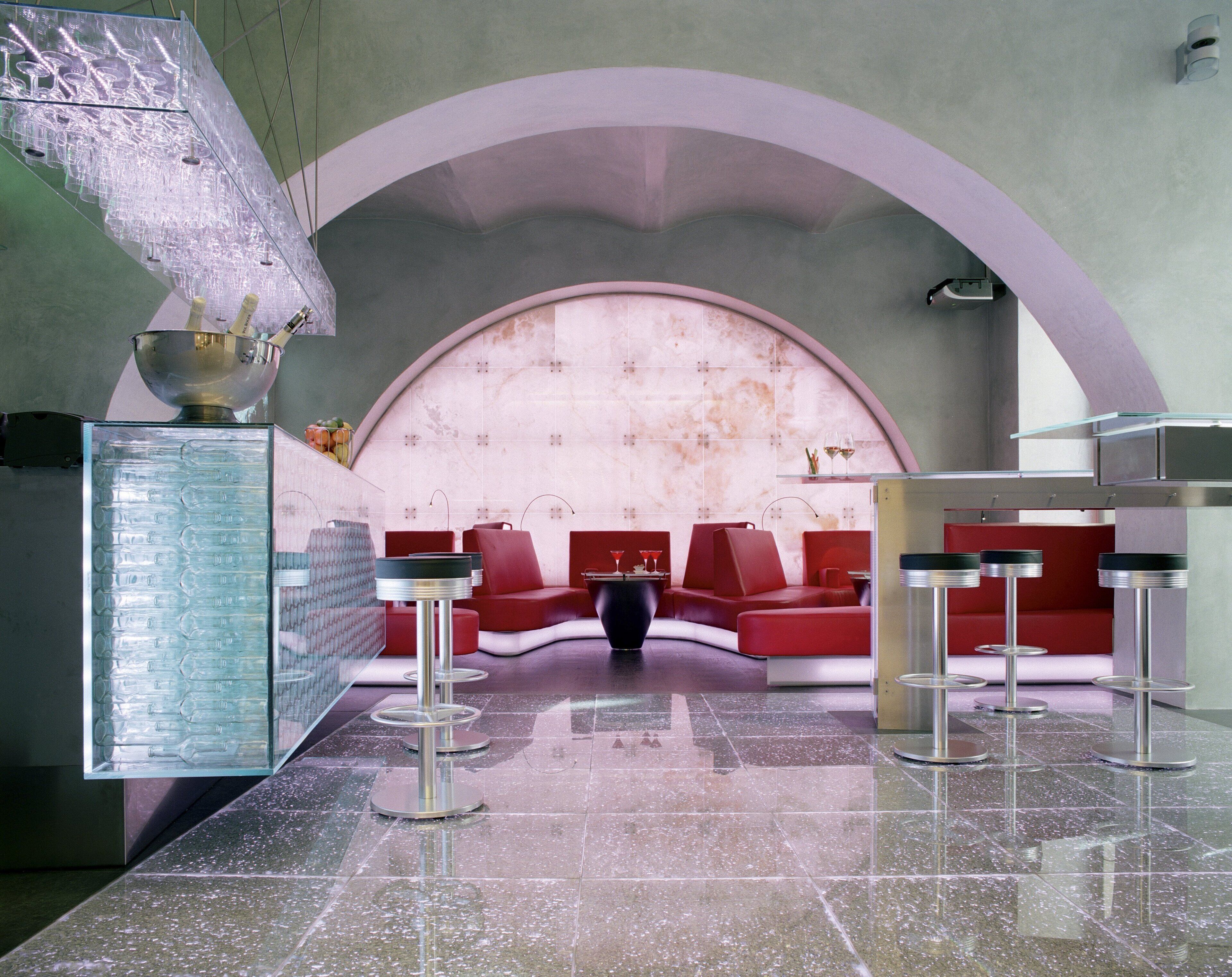 A modern interior with a curved seating area, a glass sculpture, and a marble floor.