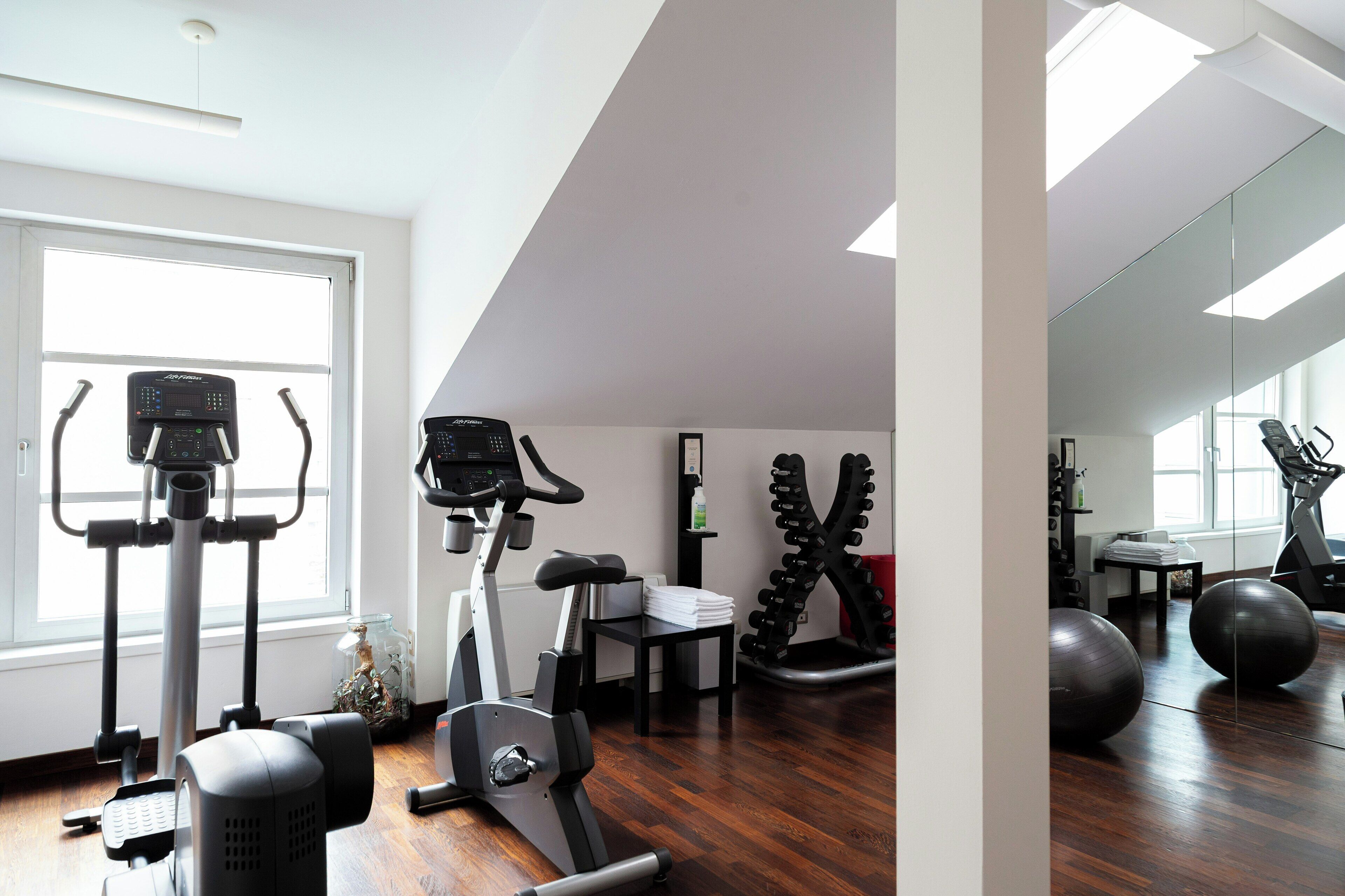 A home gym with exercise equipment, a large mirror, and a view of the outdoors.