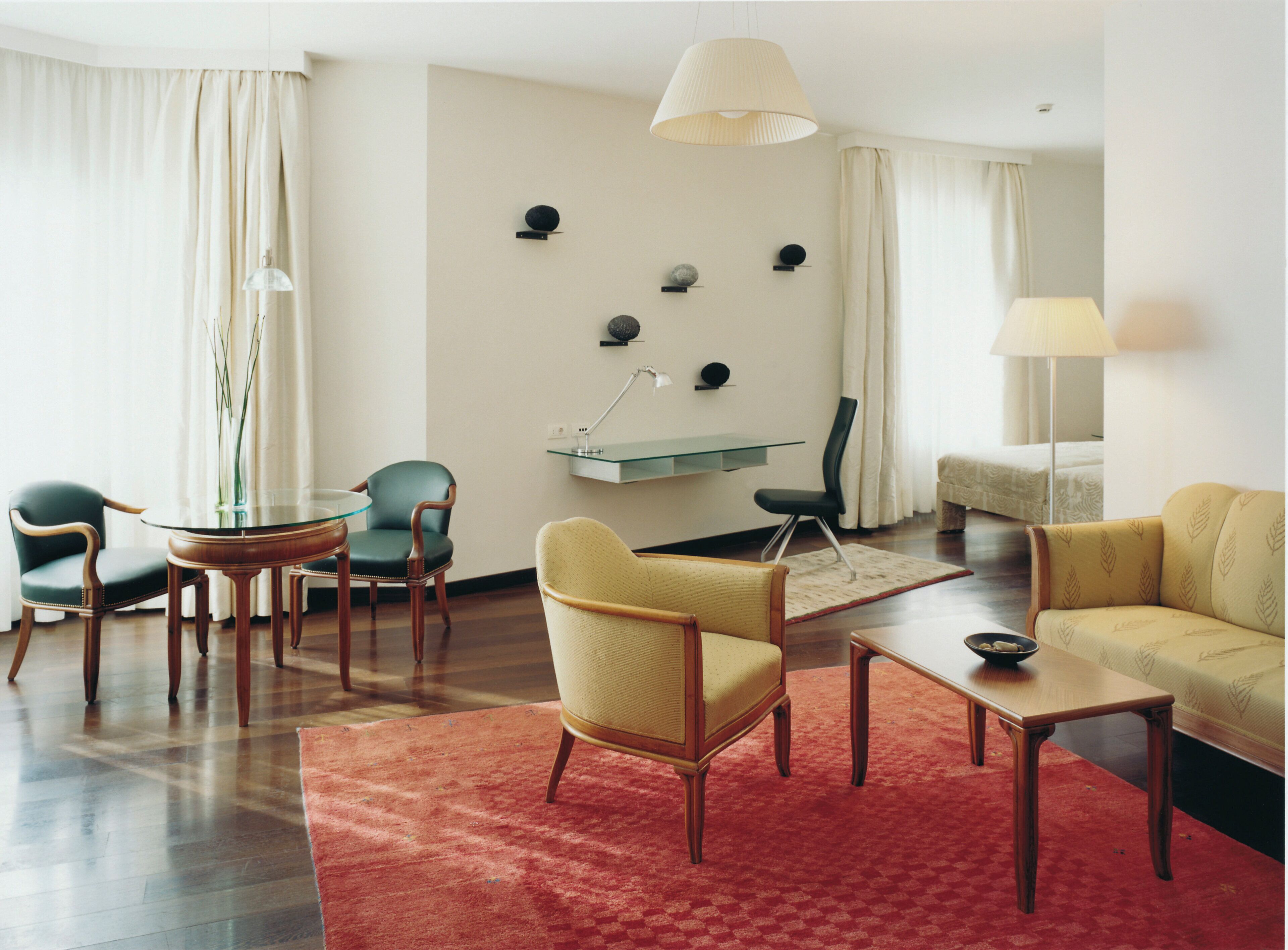 A modern living room with a glass coffee table, a red rug, and a sofa.