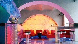 A modern lounge area with red seating, a large arched wall, and a reflective floor.