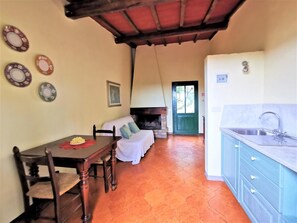 A cozy interior with a dining table, a sofa, a fireplace, and a kitchen area. - Fattoria il Bacio (Certaldo)