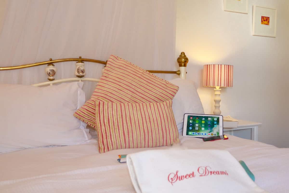 A neatly made bed with striped pillows, a bedside lamp, and a tablet on the nightstand.