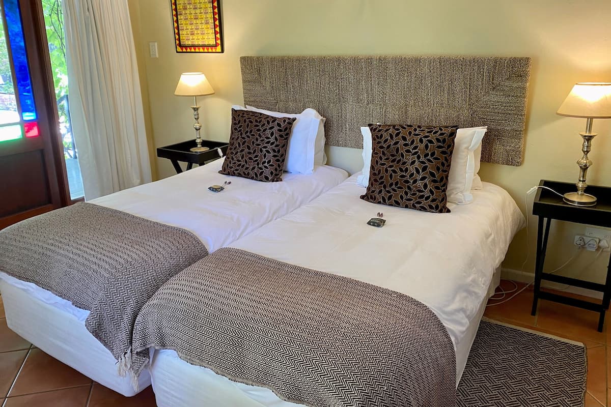 A large bed with patterned pillows and a matching throw, two bedside tables with lamps, and a wall-mounted artwork.