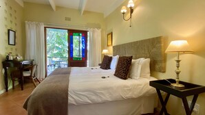A hotel room with a large bed, two bedside lamps, a desk, and a view of the outdoors.