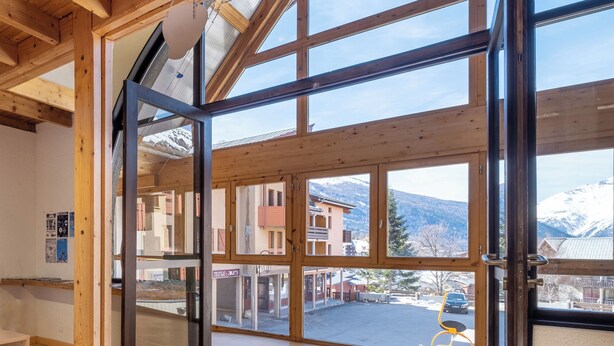 A spacious room with large windows, wooden beams, and a view of a mountain landscape. - VVF Val-Cenis Haute-Maurienne (Val-Cenis)