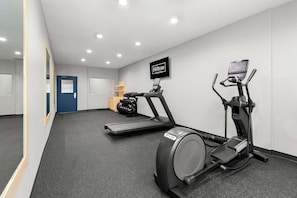 A hotel fitness room with treadmills, an elliptical, and a TV screen displaying 'Hilton Honors.' - Spark by Hilton Missouri City (Missouri City)