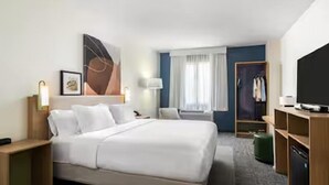 A hotel room with a large bed, bedside tables, a TV, a wardrobe, and a window with curtains. - Spark by Hilton Missouri City (Missouri City)