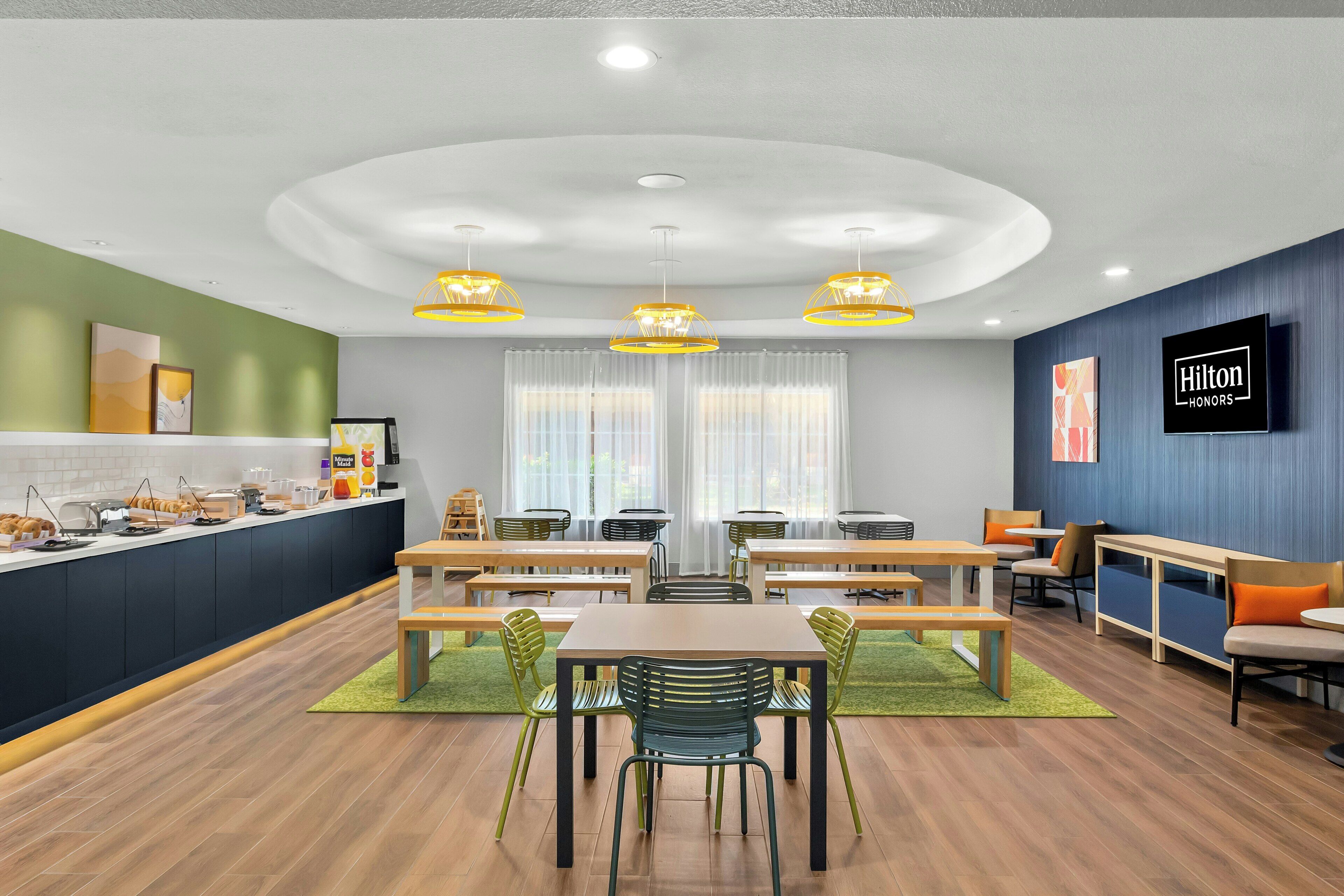 A modern hotel room with a kitchen area, dining space, and seating area.