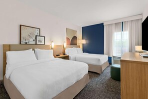 A hotel room with two beds, a desk, a chair, and a window with curtains. - Spark by Hilton Missouri City (Missouri City)