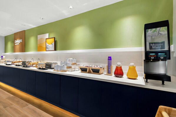 A breakfast bar with various food items, a coffee machine, and a 'Minute Maid' sign. - Spark by Hilton Missouri City (Missouri City)