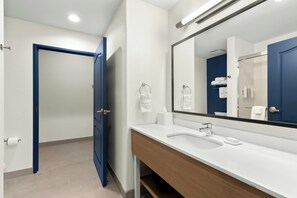 Un baño moderno con un lavamanos blanco, un espejo grande y una puerta azul.