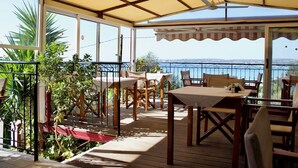 A covered outdoor patio with wooden furniture, a ceiling fan, and a view of the sea. - Agios Gerasimos (Kefalonia)