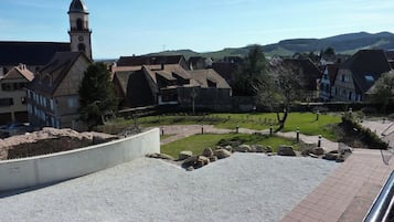 A rural village with traditional houses, a church tower, and a paved area with rocks and a pathway.