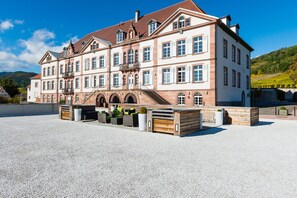 A large, historic building with multiple windows and a central staircase. - Val-vignes Haut-koenigsbourg, The Originals Relais (Saint-Hippolyte)