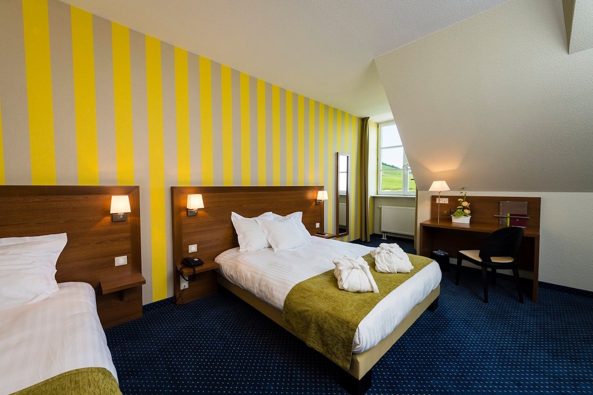 Une chambre d’hôtel avec deux lits, un bureau et une chaise.