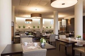 A spacious hotel dining area with multiple tables and chairs, large pendant lights, and potted plants. - Val-vignes Haut-koenigsbourg, The Originals Relais (Saint-Hippolyte)