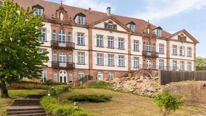 A multi-story building with a symmetrical facade, large windows, and a central entrance with a staircase. - Val-vignes Haut-koenigsbourg, The Originals Relais (Saint-Hippolyte)