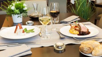 A dining table set with plates of food, wine glasses, and cutlery.