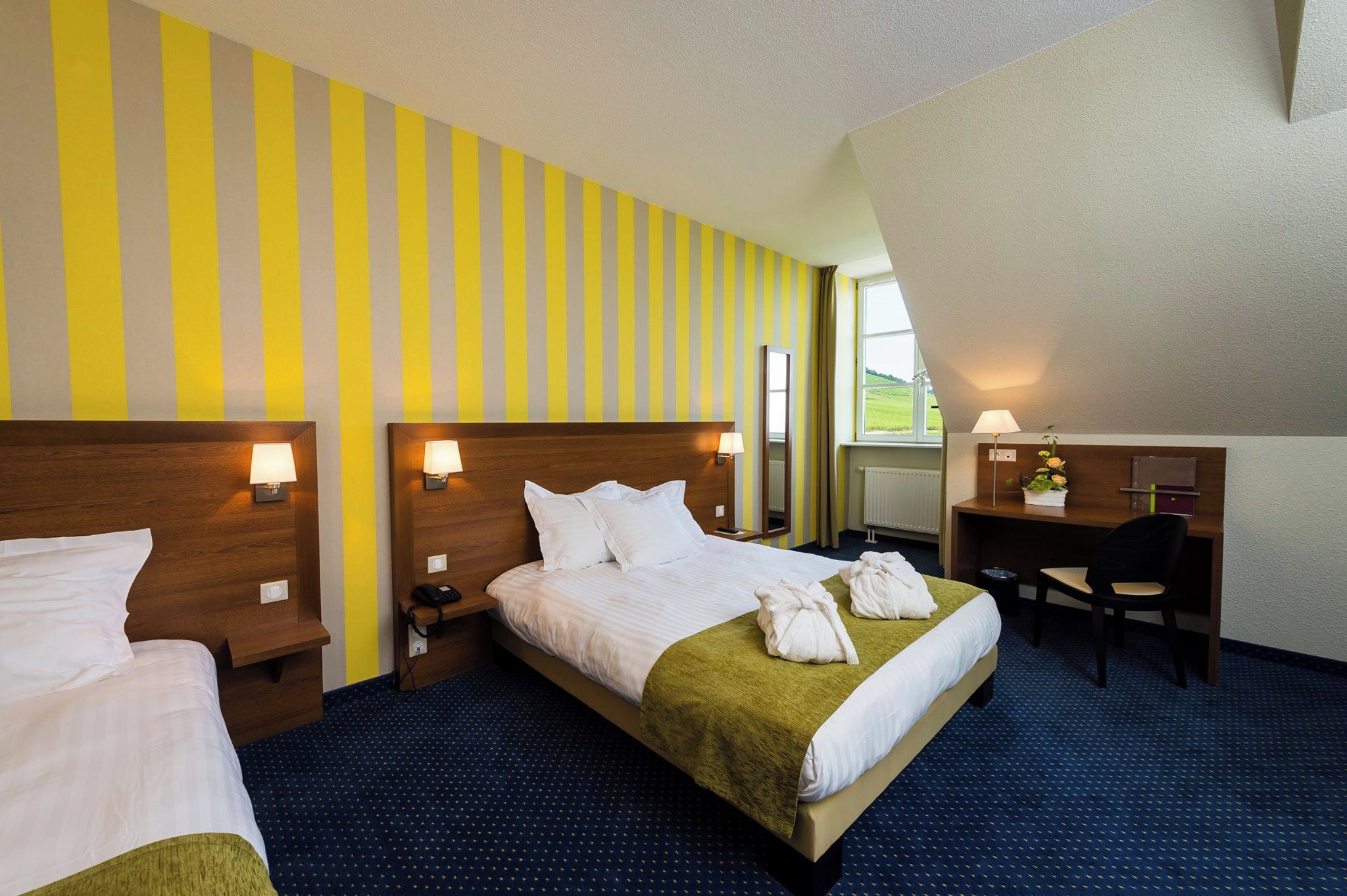 Ein Hotelzimmer mit zwei Betten, einem Schreibtisch und einem Stuhl.