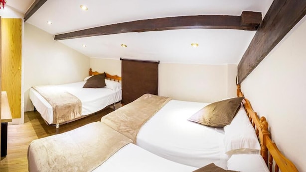 A room with two single beds, wooden headboards, and a wooden ceiling beam. - Les Neus (Pas de la Casa)