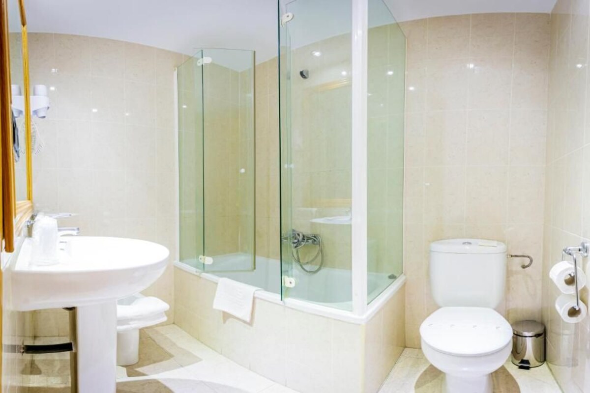 A modern bathroom with a glass-enclosed shower, a white sink, and a toilet.