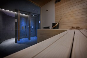 A modern spa room with a glass-enclosed shower, wooden paneling, and a wooden bench. - Hotel Cristallo (Livigno)