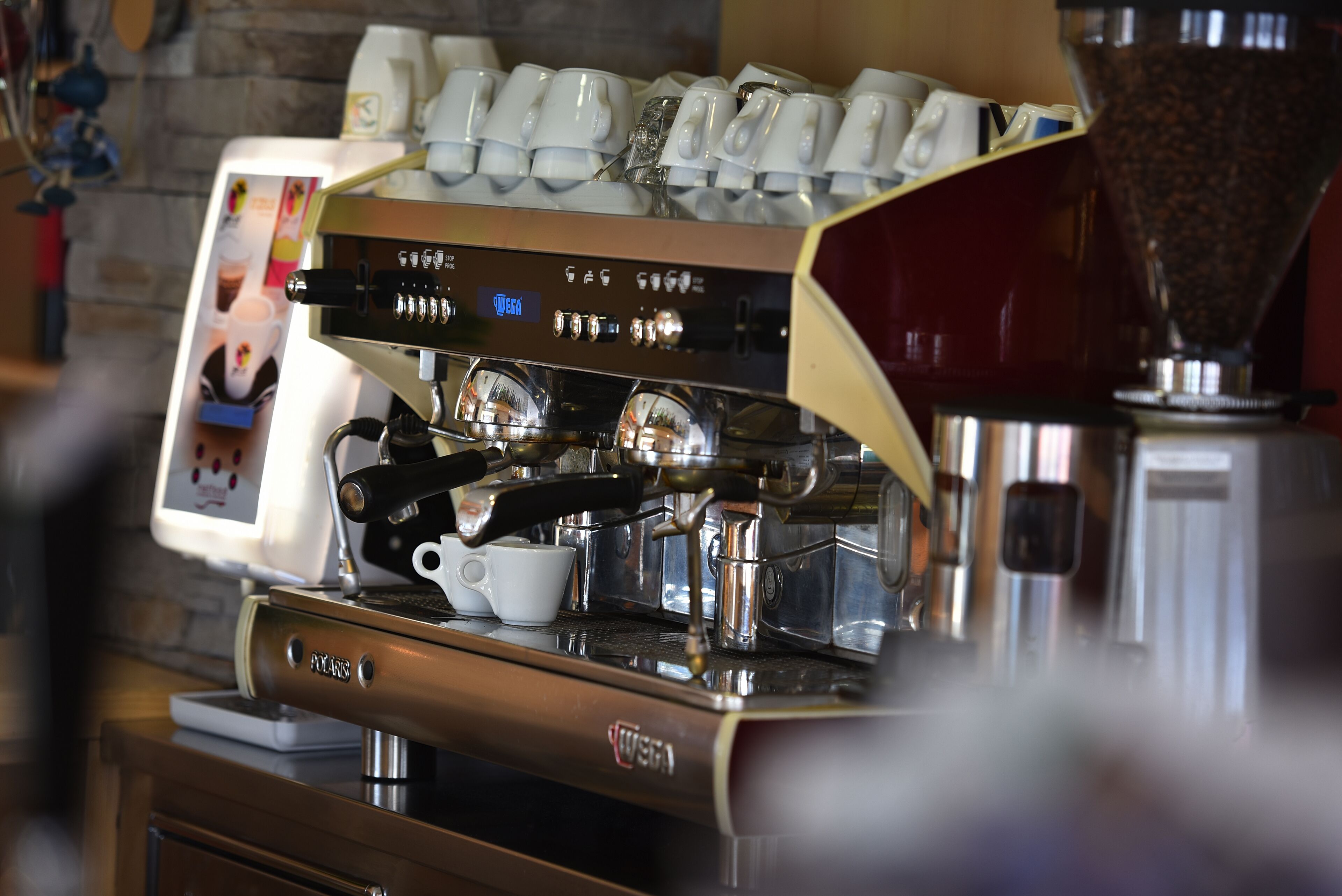 Een koffieapparaat met daarboven een stapel koffiekopjes.