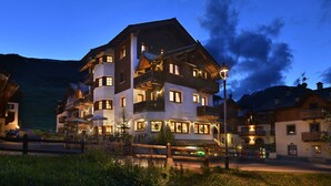 Un hotel de varios pisos con balcones, mesas al aire libre y un letrero que indica que es un restaurante.