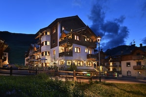 A multi-story hotel with balconies, outdoor seating, and a sign indicating it is a restaurant. - Hotel Cristallo (Livigno)