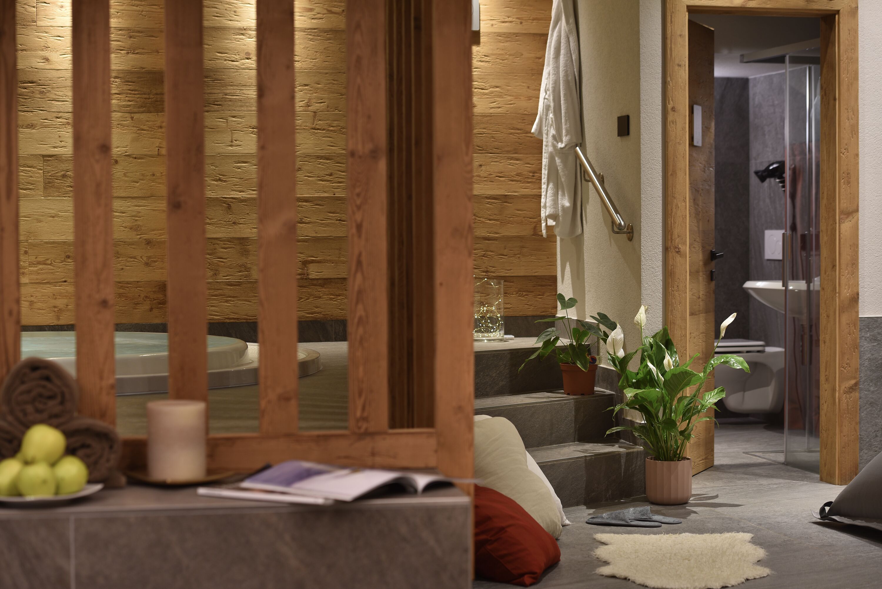 Un cuarto de spa con pared de madera, una bañera, una planta en maceta y un perchero para toallas.
