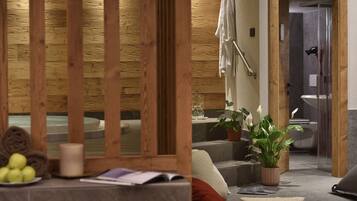 Un cuarto de spa con pared de madera, una bañera, una planta en maceta y un perchero para toallas.