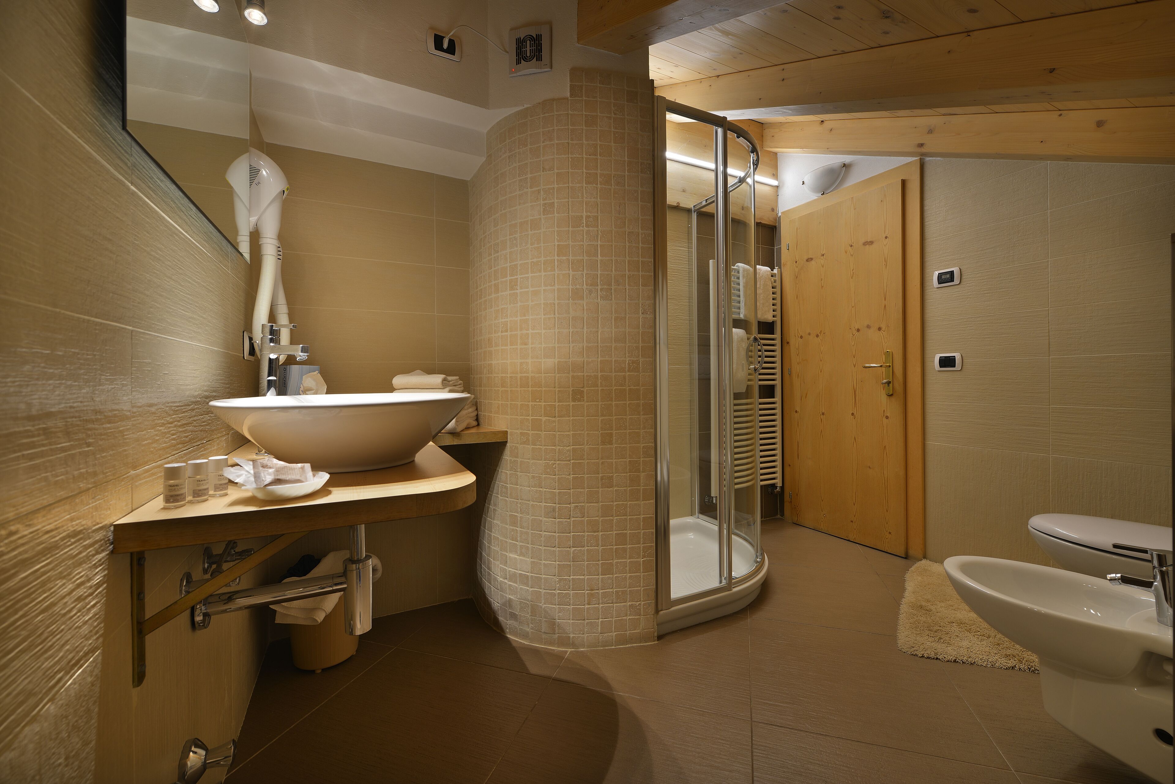 Ein modernes Badezimmer mit einem großen Waschbecken, einer Duschkabine aus Glas und einer Holztür.