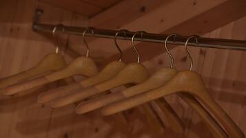 Wooden hangers on a metal rack against a wooden wall.