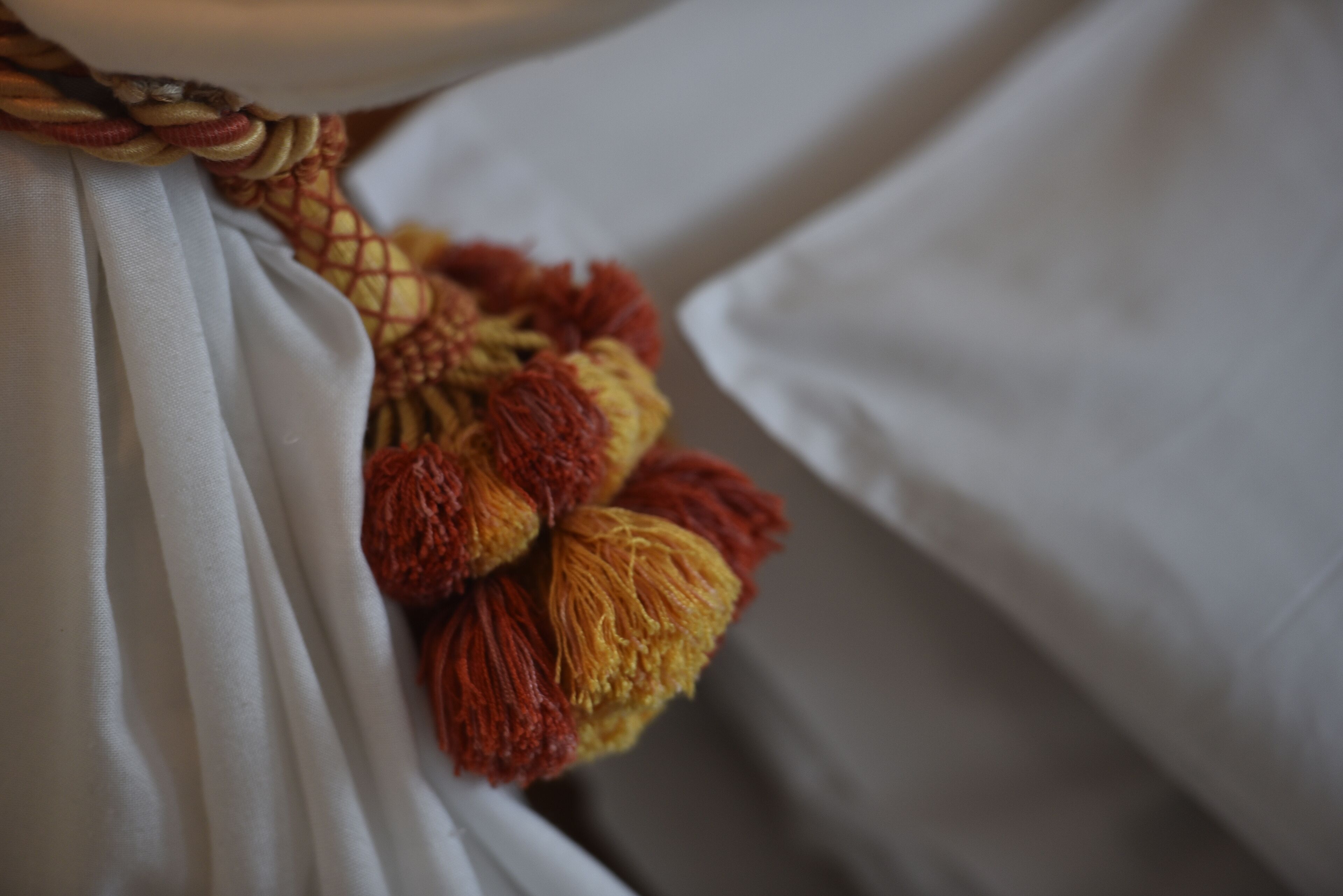 A close-up of a bed with white sheets and a decorative tassel.