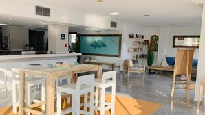A spacious room with a wooden dining table, white chairs, a large window, and a bookshelf filled with books. - Sa Torre (Capdepera)