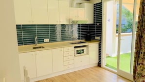 A modern kitchen with white cabinets, a microwave, and a sink. - Sa Torre (Capdepera)