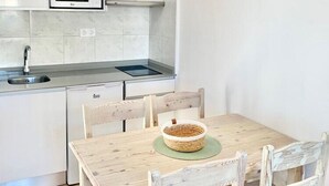 A modern kitchen with white cabinets, a microwave, and a hanging light fixture. - Sa Torre (Capdepera)