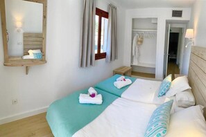 A double bed with teal bedding, a wooden headboard, and a mirror on the wall. - Sa Torre (Capdepera)