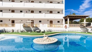 A hotel with a swimming pool, outdoor seating, and a covered area. - Sa Torre (Capdepera)